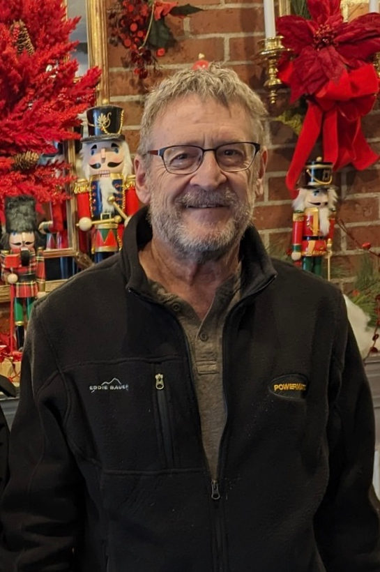 Craig, owner of Wilson Woodworking, smiling in front of a decorated fireplace.